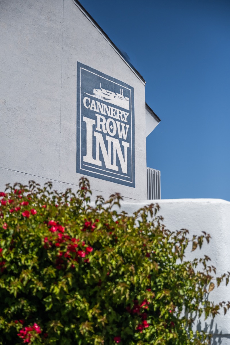 Painted Cannery Row Inn logo on the gable above blooming bougainvillea