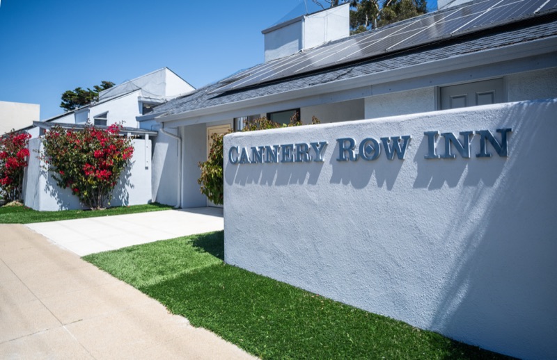 Cannery Row Inn letters on the white entry wall with bougainvillea