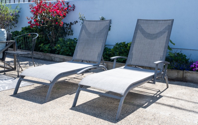 Two chaise lounges against a white wall with bougainvillea