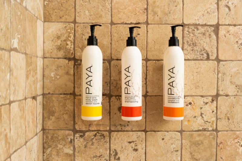 PAYA bath amenities on travertine shower tile