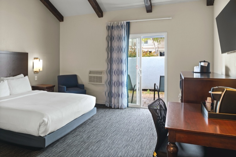 King room with bed, armchair, desk, and sliding door to a private patio
