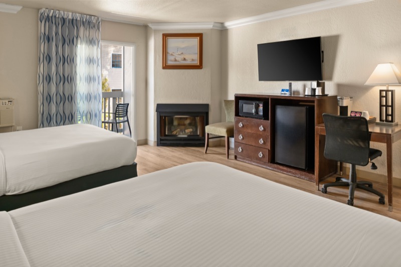 Lit fireplace and wall-mounted TV across from two queen beds
